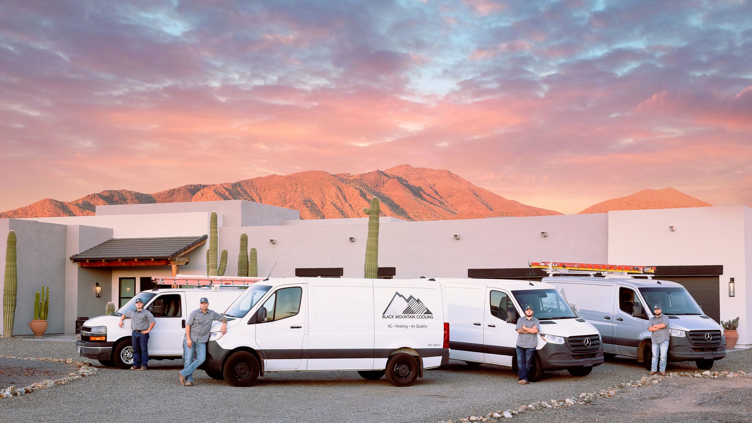 Black Mountain Cooling vans and team in front of a desert home at sunset