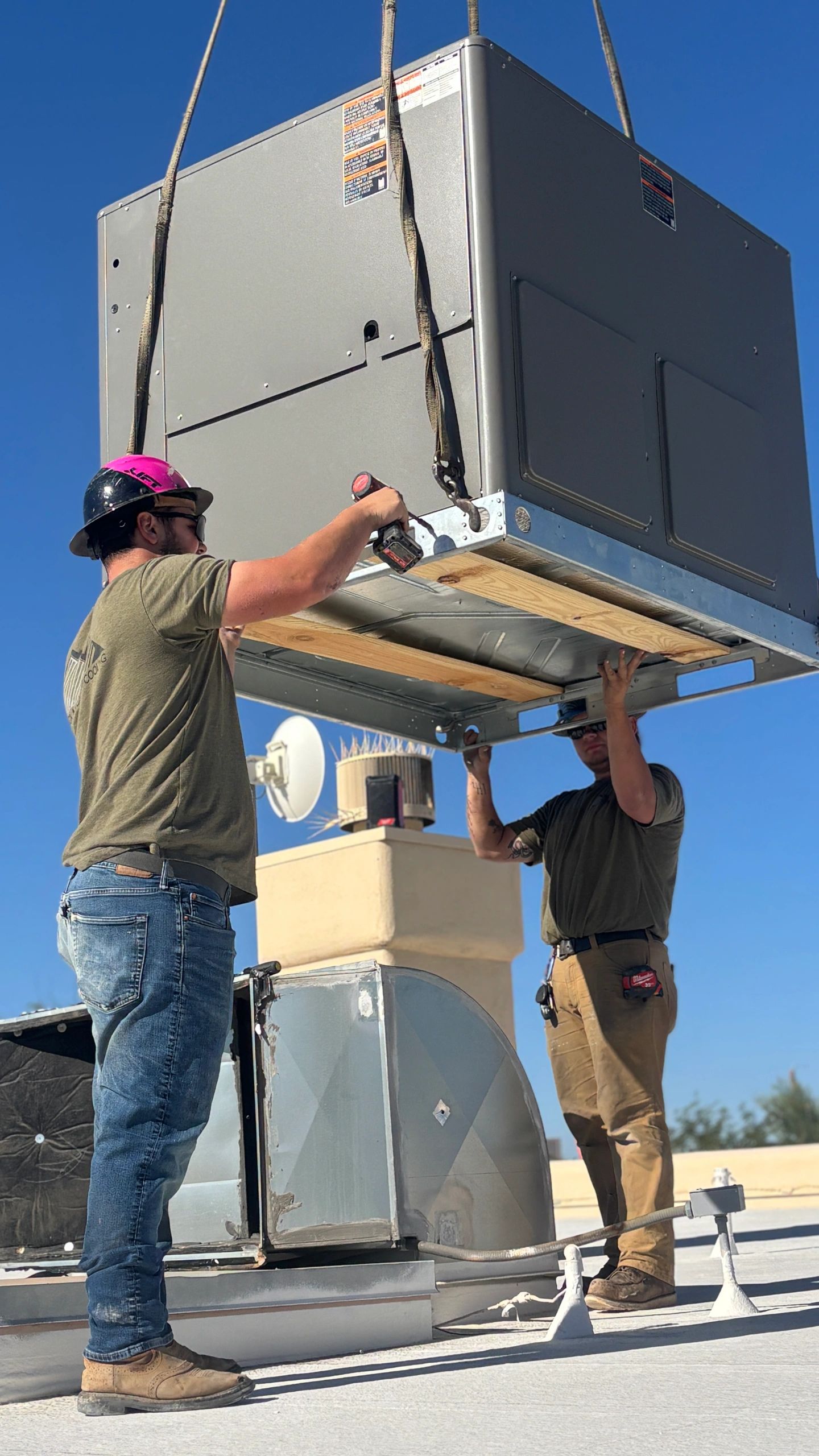 Technicians installing a rooftop HVAC unit